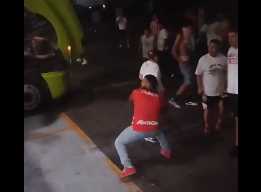 Aficionado con playera de Chivas lanza una piedra al camión. Foto: Redes Sociales