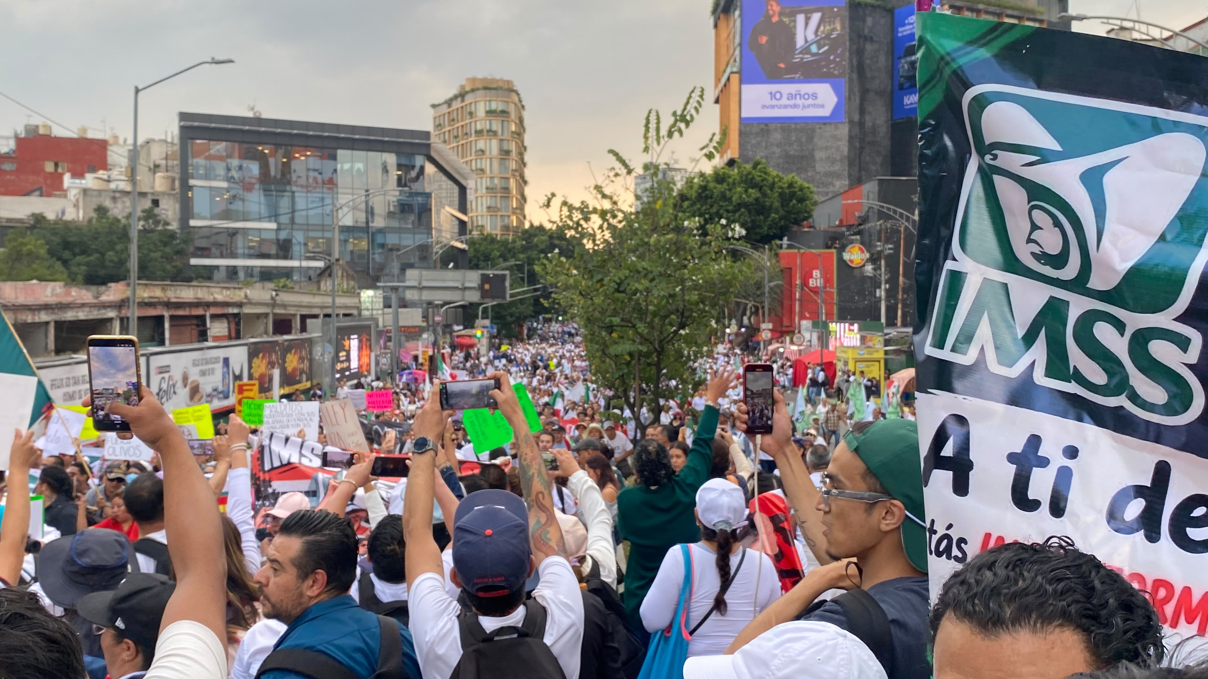 Manifestantes de la marcha del IMSS avanzan con pancartas y banderas sobre la Avenida Insurgentes en la Ciudad de México