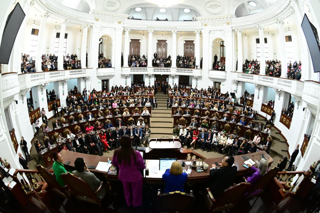 Vista panorámica del interior del Congreso de la Ciudad de México, con Clara Brugada de espaldas con un traje rosa rindiendo su segundo informe de gobierno ante un pleno lleno de legisladores.
